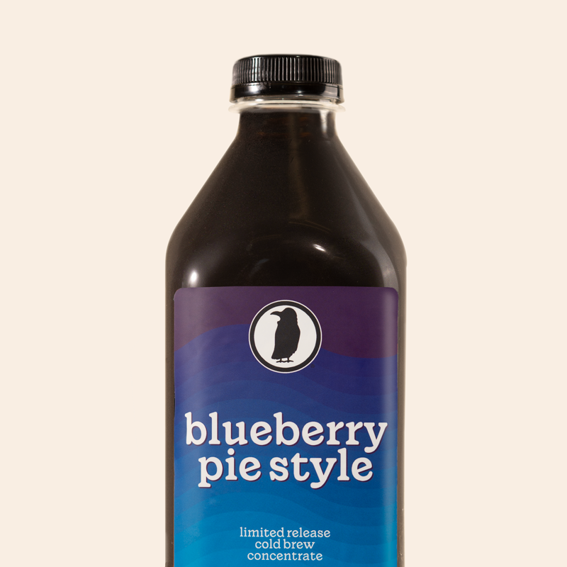 A bottle of Rook Coffee Blueberry Pie Style Cold Brew Concentrate. The label features a gradient design in shades of deep purple and vibrant blue with white text that reads: "blueberry pie style" and "limited release cold brew concentrate."