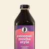 A 32-ounce bottle of Rook Coffee Coconut Mocha Style cold brew concentrate. The bottle has a black cap and dark body, with a label featuring the Rook Coffee logo at the top and a gradient background shifting from purple to pink-orange. The text reads “coconut mocha style, limited release cold brew concentrate.”