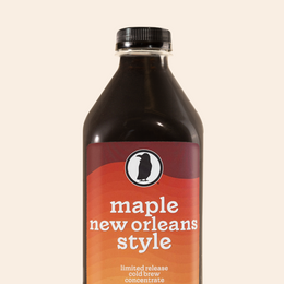 A bottle of Rook Coffee's Maple New Orleans  Style cold brew concentrate with a maroon and orange gradient label.