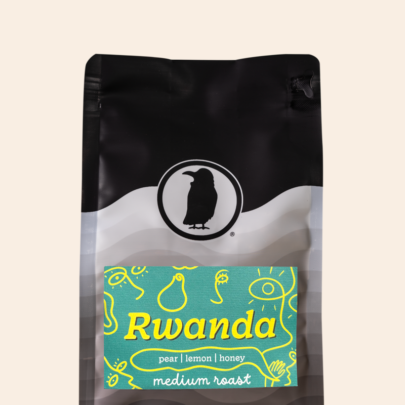 Bag of Rook Coffee Rwanda medium roast coffee featuring the Rook Coffee logo and a turquoise label with yellow illustrations. The label lists tasting notes of pear, lemon, and honey. Product shown against a transparent background.