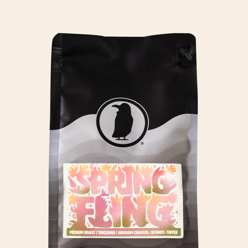 Rook Coffee bag featuring the Rook Coffee logo and a “Spring Fling” label with colorful floral lettering. The label notes a medium roast with flavor notes of graham cracker, coconut, and toffee, set against a neutral background.