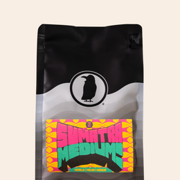 A Rook Coffee branded bag of Sumatra Medium coffee, featuring a black and white wavy design and a bright yellow label displaying 'SUMATRA MEDIUM' in pink, green, and blue text.