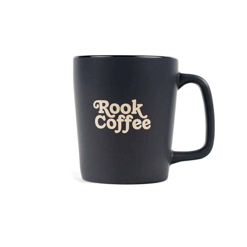 A black ceramic mug with 'Rook Coffee' in gold text