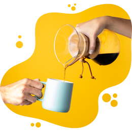One hand pours coffee from a Chemex into a light blue mug held by another hand, set against a bright yellow background with abstract bubble shapes.