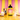 Bottle of Cinnamon Vanilla Style cold brew concentrate with a glass of iced coffee, scoops of ice cream, cinnamon sticks, and an upside-down cone on a bright yellow surface with pink and yellow striped background.