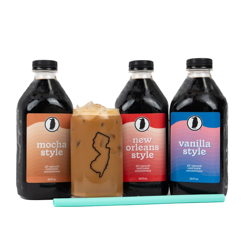 Three Rook Coffee cold brew bottles labeled Mocha Style, New Orleans Style, and Vanilla Style behind a glass of cold brew with a mint green straw.
