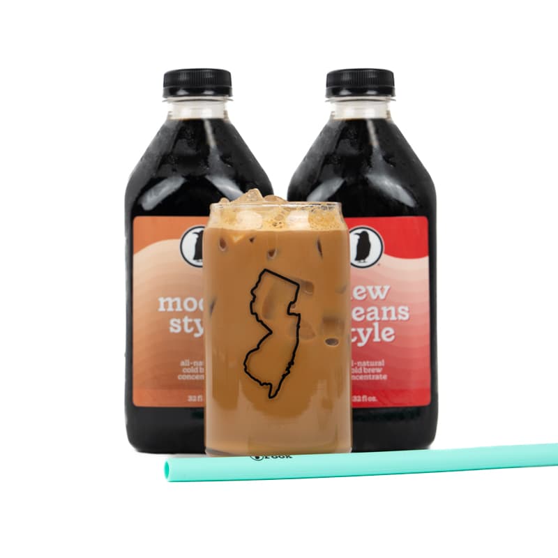 Two Rook Coffee cold brew bottles behind a glass of cold brew with a mint green straw.