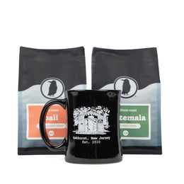 Black mug with a white illustration of the original Rook Coffee, placed in front of two Rook Coffee bags.