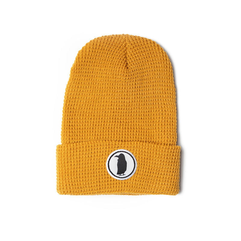 A gold knit beanie with a Rook Coffee logo on the brim