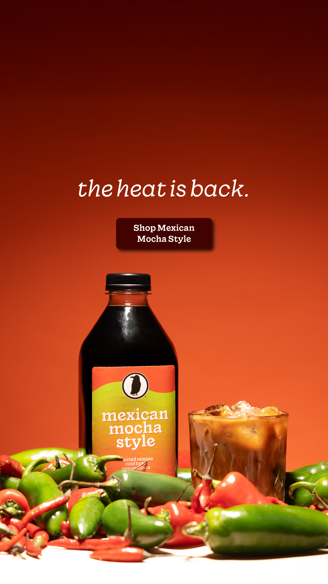 Bottle and glass of Rook Coffee Mexican Mocha Style cold brew surrounded by red and green chili peppers on orange background.