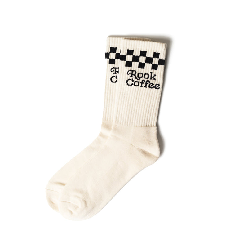 A pair of white socks with black and white checkers on the top and 'Rook Coffee' stitched in black writing